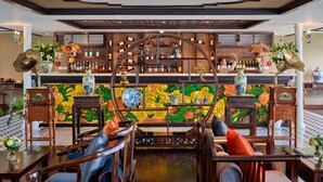 Una zona de bar con estantes de madera, un mural colorido y una variedad de botellas y vasos.