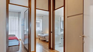 A corridor with wooden doors leading to a bedroom with a bed and a bathroom with a shower. - The. Loft. by. Guido (Vicenza)