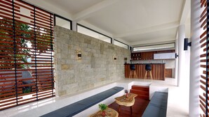 A modern interior with a stone wall, wooden slats, and a kitchen area. - Villa Luna (Kuta)