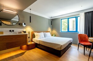 Quarto moderno com cama de madeira, mesa de cabeceira, espelho e janela com cortinas.