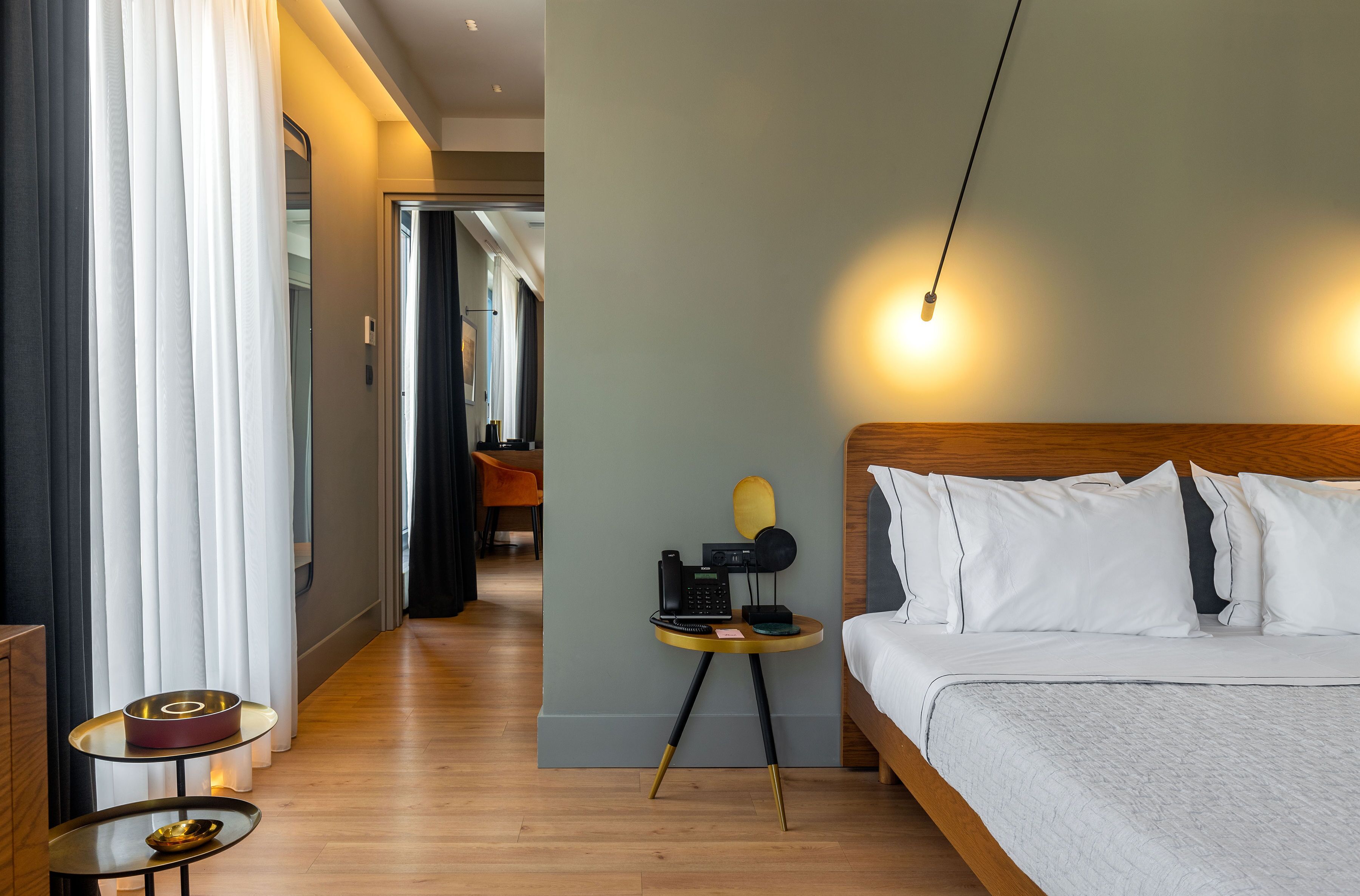 A hotel room with a bed, bedside table, and a lamp.