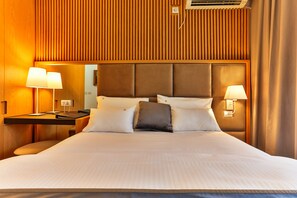 A hotel room with a large bed, two bedside lamps, a wooden headboard, and a nightstand with a lamp. - Villa Dvor Kornic (Budva)