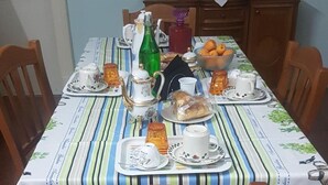 A dining table set with various dishes and drinks, surrounded by wooden chairs. - B&B Miraglia (Naples)
