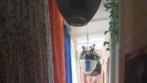 A hallway with patterned curtains, a hanging flower pot, and a tiled floor. - B&B Miraglia (Naples)