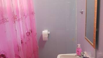 A bathroom with a pink shower curtain, a sink with a mirror, and a small rug on the floor.