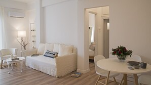 Ett modernt, minimalistiskt vardagsrum med en soffa, två fåtöljer, ett litet bord och en matplats.