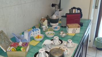 Een koffiezetapparaat/waterkoker, een koelkast, een oven, een kookplaat