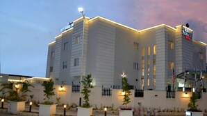 Et hotel med en moderne facade, mange vinduer og en godt oplyst indgang.