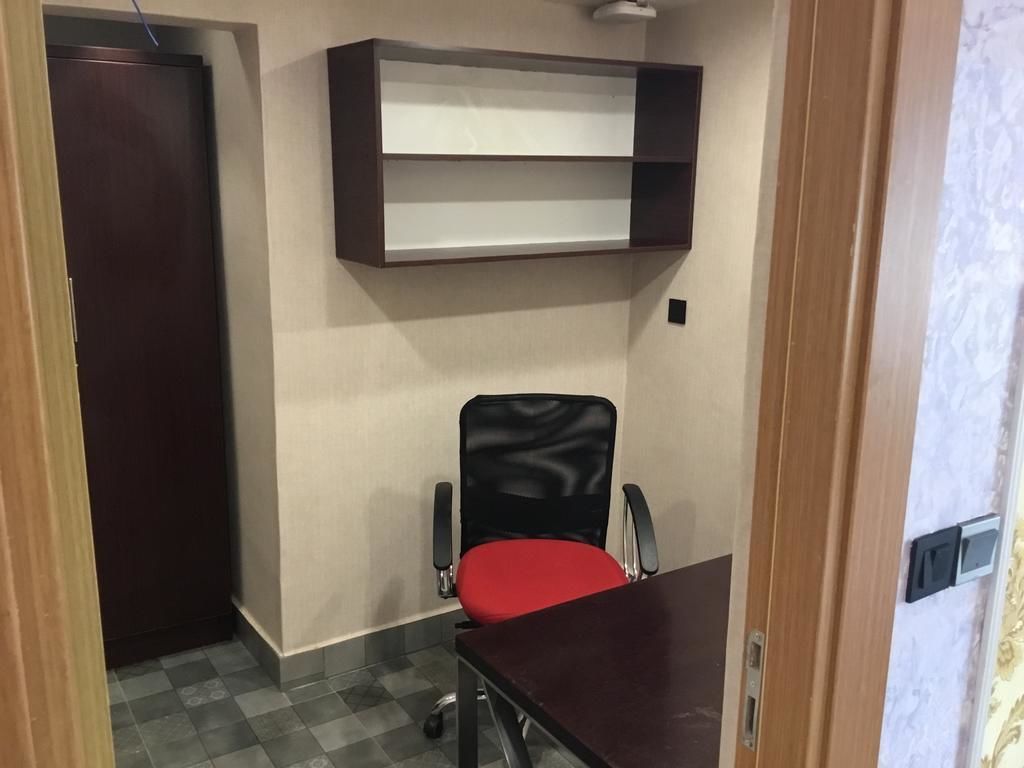 A small office space with a desk, a chair, and a shelf unit.