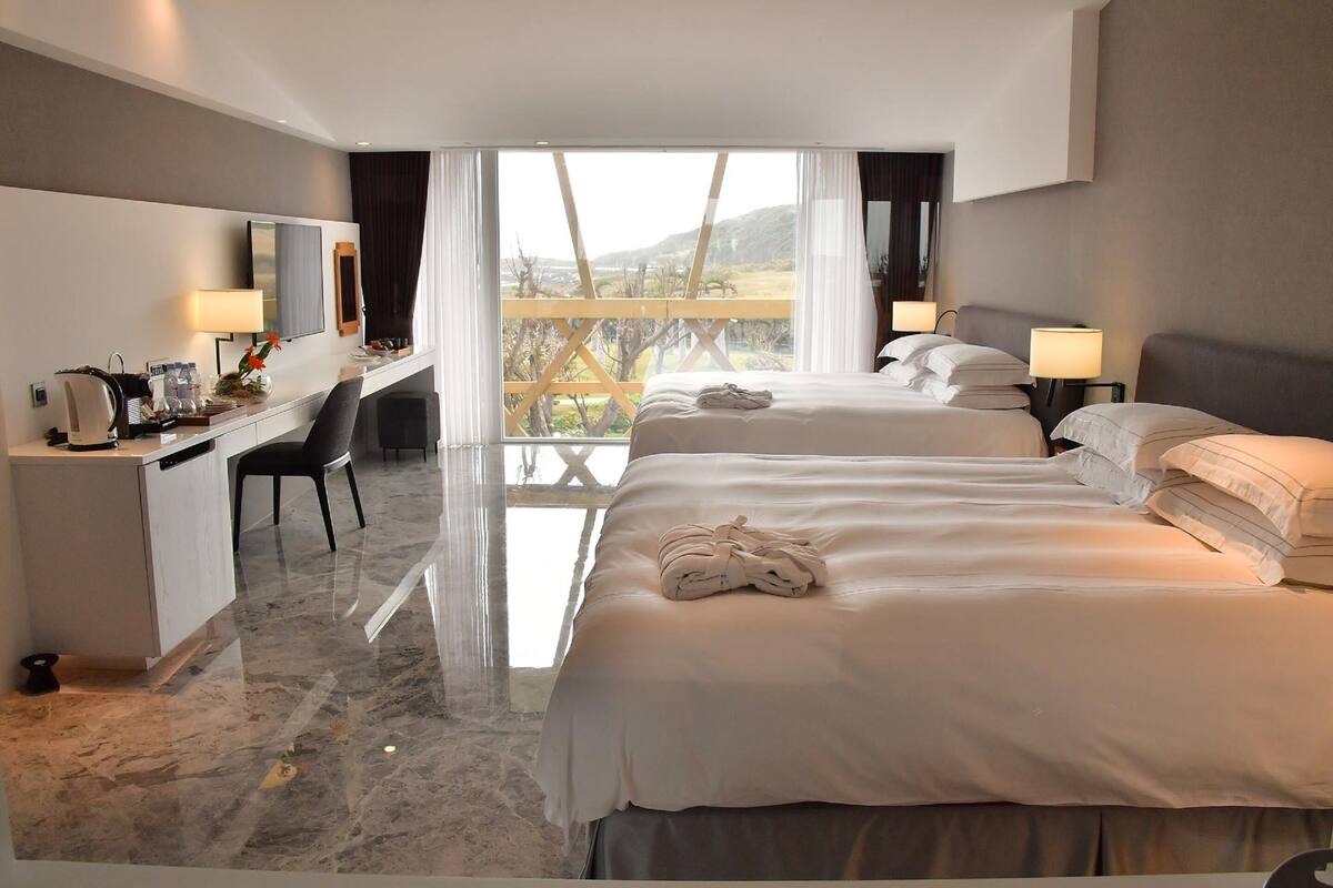A hotel room with a large bed, a desk, and a view of a balcony.