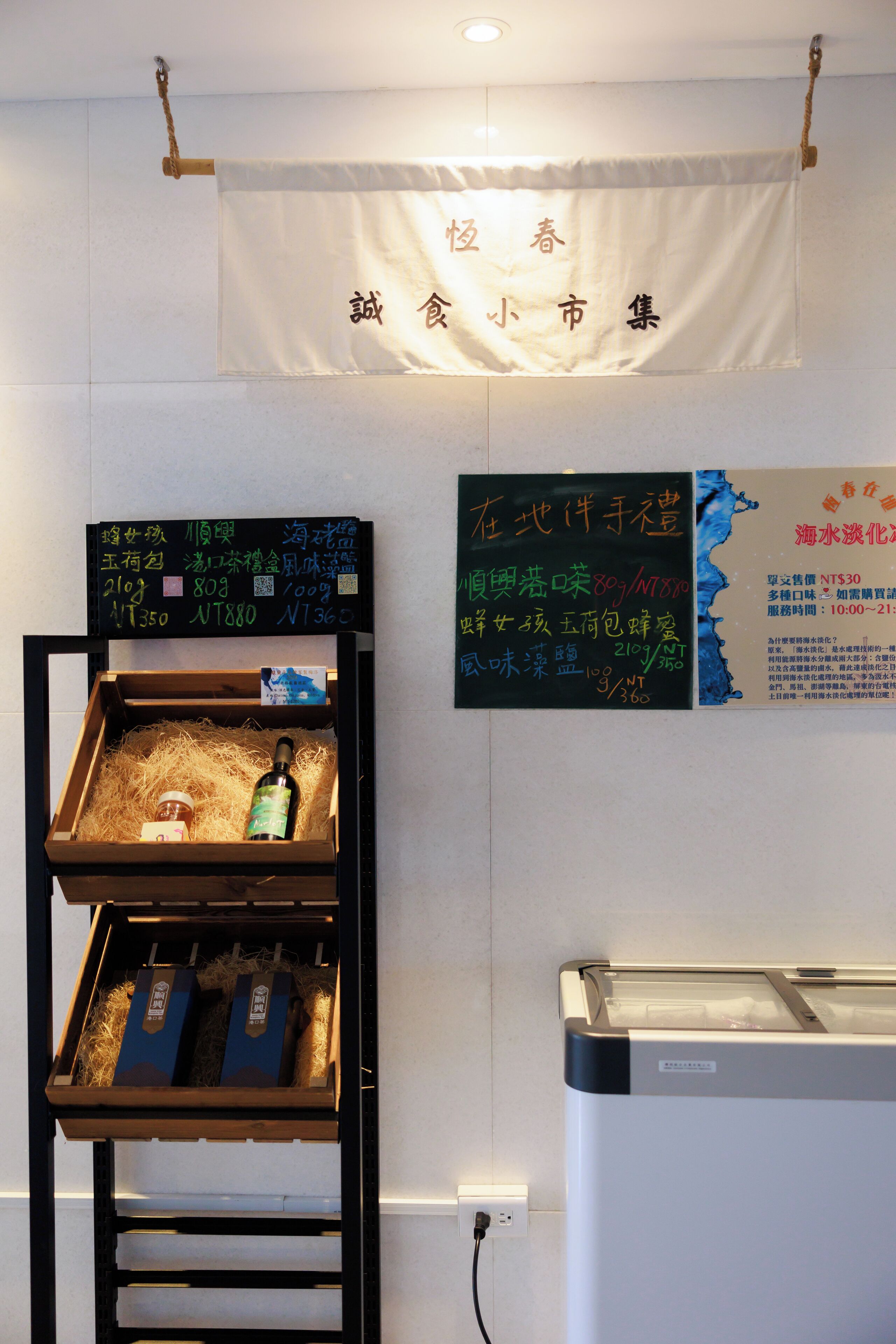 A restaurant interior with a wooden display case containing food items and a chalkboard menu.
