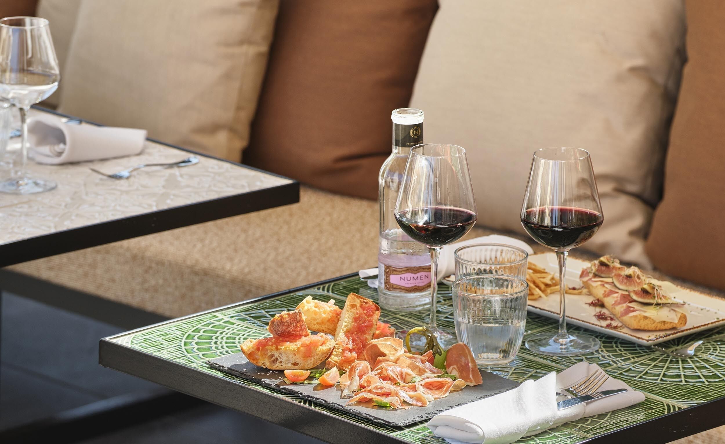 Una mesa de comedor con diversos platos, copas de vino y una botella de vino.