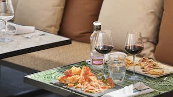 Una mesa de comedor con diversos platos, copas de vino y una botella de vino.
