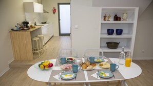 Eine moderne Küche mit Esstisch, gedeckt für ein Frühstück, darunter Teller mit Eiern, Toast und Obst.