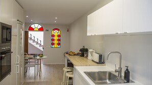 Eine moderne Küche mit Holzausziehtisch, Edelstahlspüle und einem Toaster. Eine Treppe führt in eine obere Ebene.