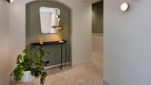 Ein Flur mit modernem Design, ausgestattet mit einem Topf mit Pflanze, einem Spiegel und einer Lampe auf einer Konsole.