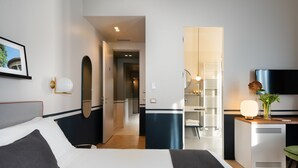 Ein Hotelzimmer mit Bett, Nachttisch, Fernseher und einem durchgegangenen Tür sichtbar liegenden Badezimmer.