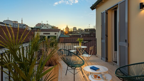 Eine Dachterrasse mit Tisch, Stühlen und Blick auf die Skyline bei Sonnenuntergang.