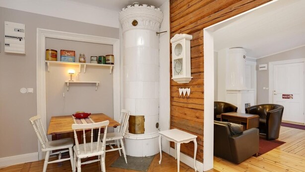 A dining area with a wooden table and white chairs, a white pillar, and a wooden wall. - Hagbackens GĂ„rd Bed & Breakfast (Ărebro)