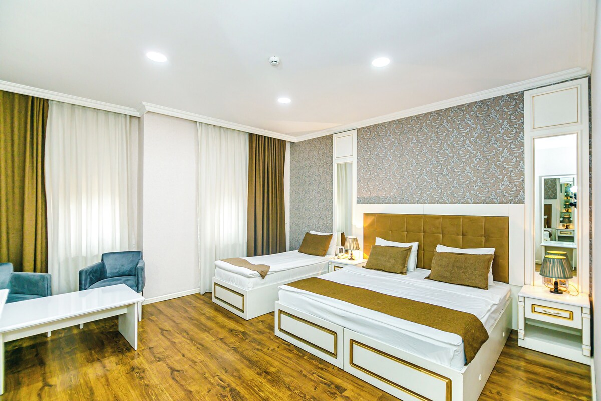 A hotel room with a large bed, a smaller bed, a desk, and a chair.