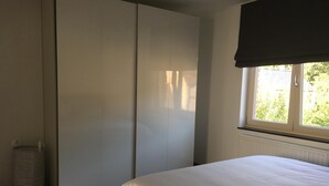 Une chambre à coucher comprenant un lit, une armoire, un radiateur et une fenêtre donnant sur un paysage verdoyant.