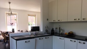 Une cuisine moderne avec des meubles blancs, un plan de travail noir et un coin repas comprenant une table et des chaises.
