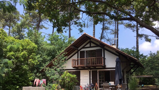 Een twee verdiepingen tellend huis met een balkon, omringd door bomen.