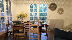Een gezellige eethoek met een houten tafel, stoelen en een bloevas.