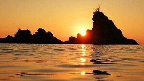 A sunset over a calm sea with rocky formations. - Campo Sportivo (Taurianova)