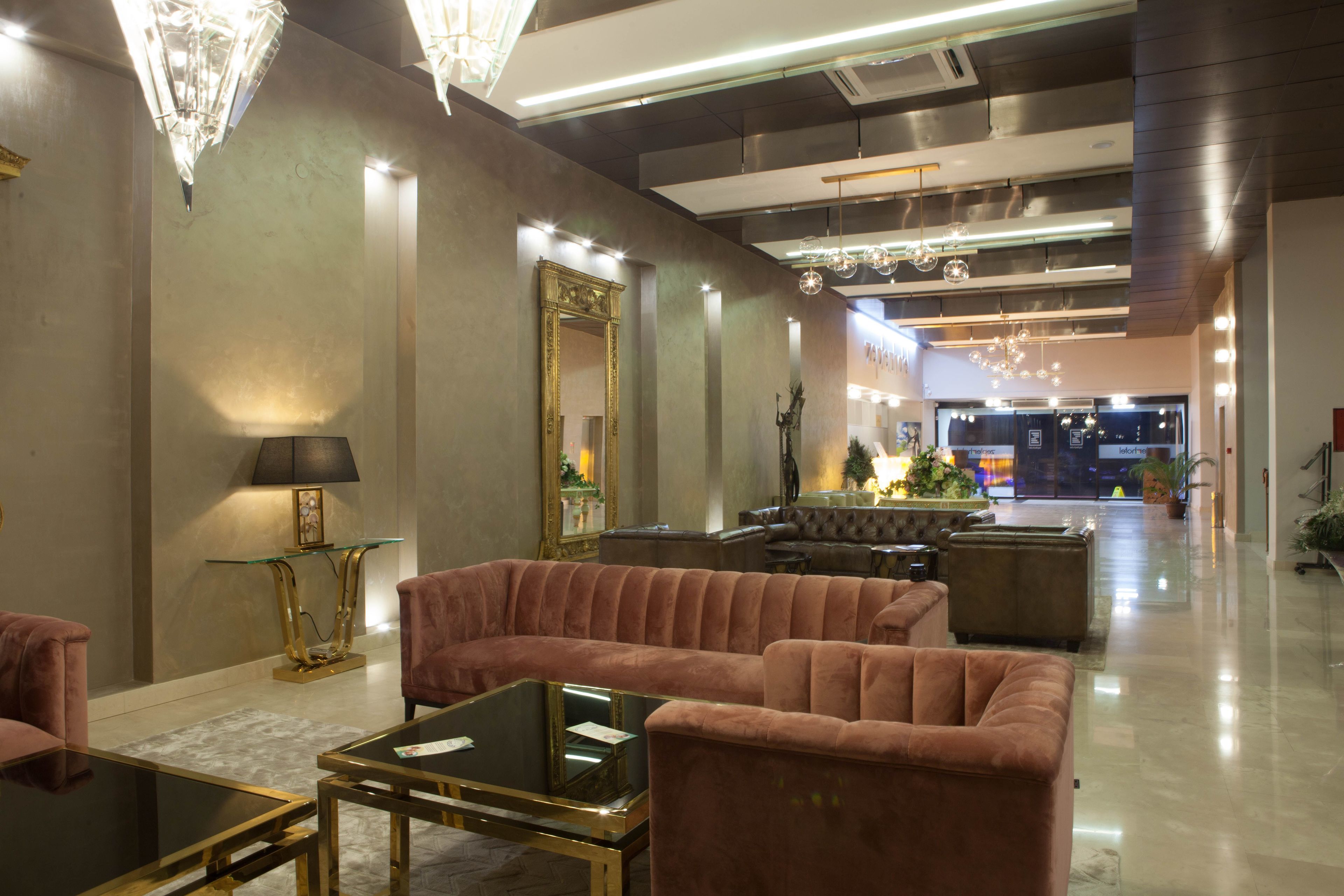 A spacious lobby with plush seating, a glass coffee table, and elegant lighting fixtures.