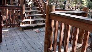 Una escalera de madera que lleva a una terraza rodeada de árboles.