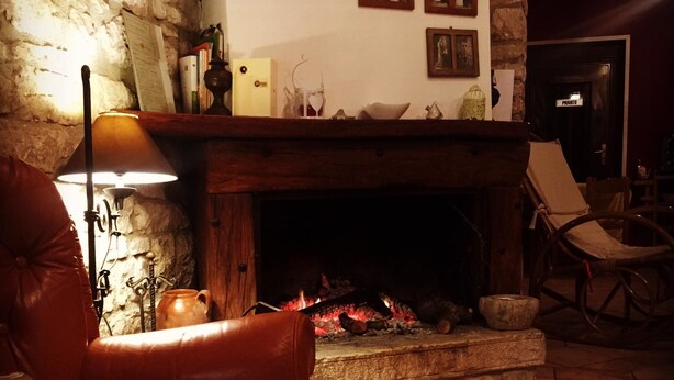 A cozy living room with a stone fireplace, leather armchair, and a tiled floor. - Masseria Frangiosa (Torrecuso)