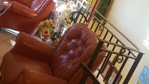 A reception area with leather chairs, a flower vase, and a poster on the wall. - Masseria Frangiosa (Torrecuso)