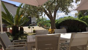 An outdoor patio with a table and chairs, surrounded by potted plants and a tree. - Masseria Frangiosa (Torrecuso)