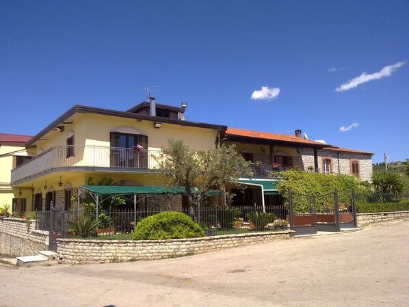 A two-story building with a balcony, a stone wall, and a green awning. - Masseria Frangiosa (Torrecuso)