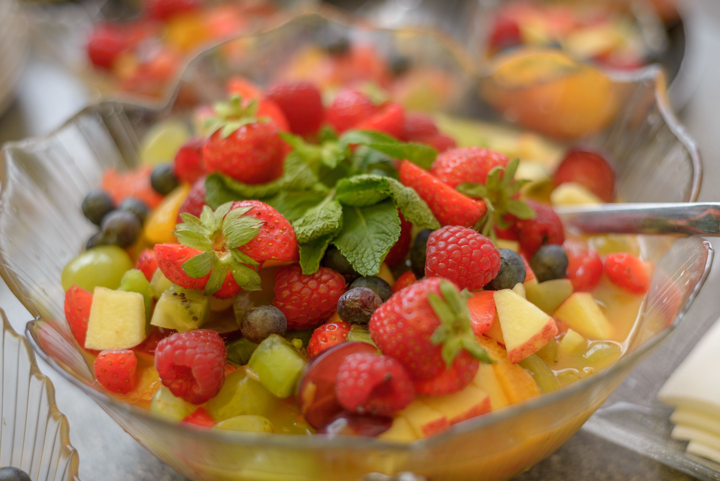 A bowl of fruit salad with strawberries, blueberries, raspberries, and other fruits.