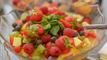 A bowl of fruit salad with strawberries, blueberries, raspberries, and other fruits.