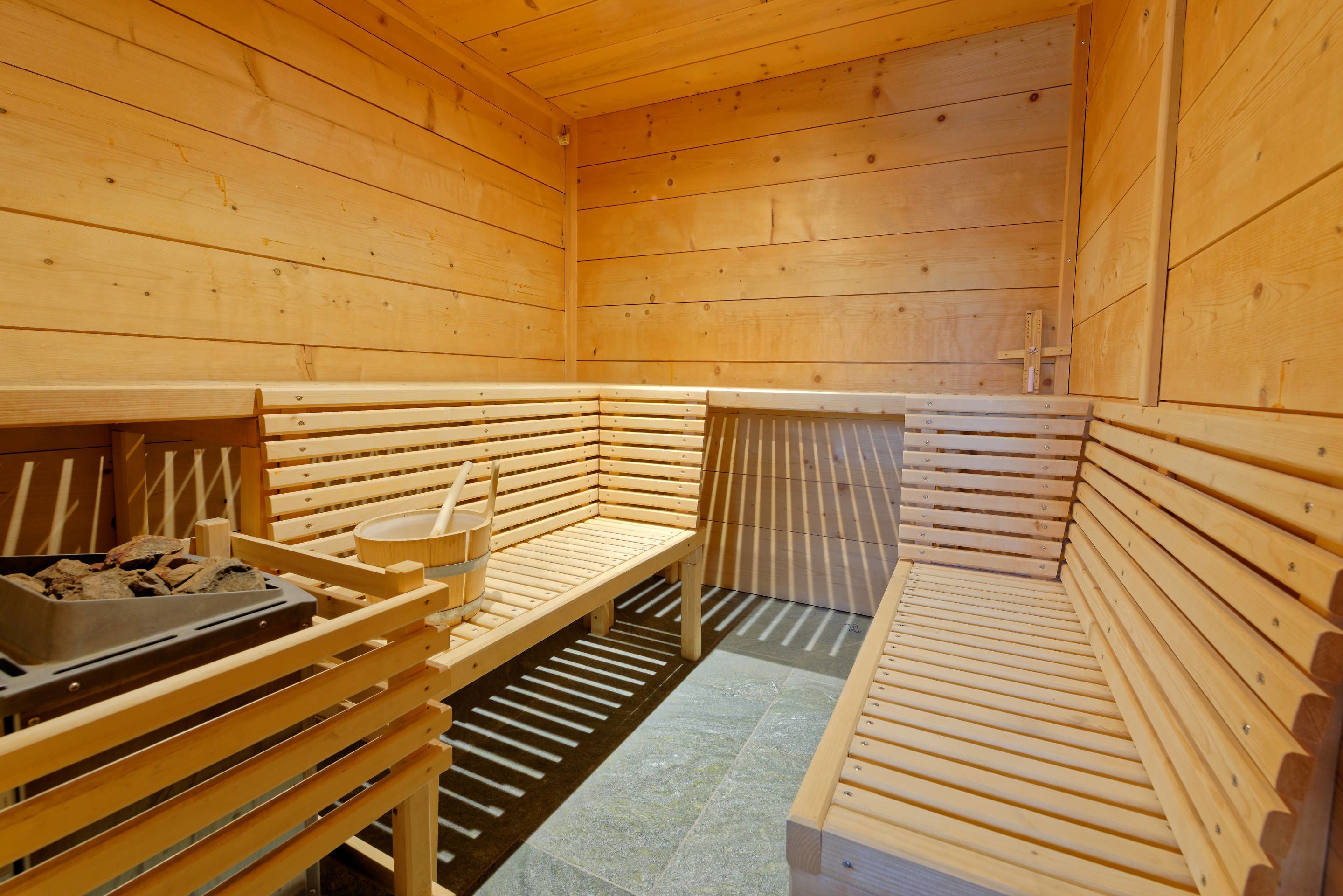 A sauna with wooden benches and a bench with a bucket.
