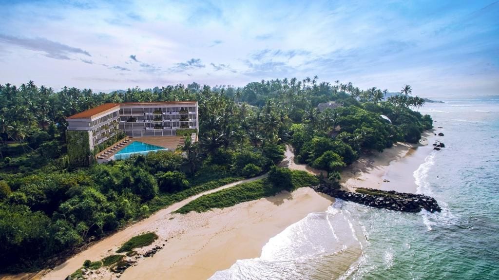 Un resort con piscina, acceso directo a la playa y exuberante vegetación tropical.