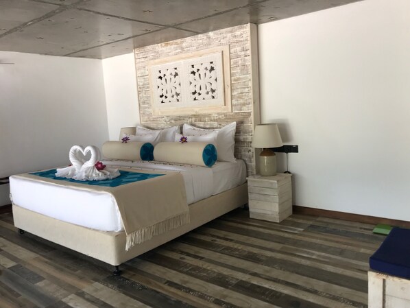 A hotel room with a large bed, a nightstand, a lamp, and a decorative wall piece.