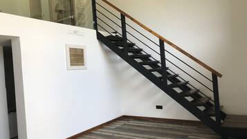 Un escalier avec une main courante en bois et des balustrades en métal noir, menant à l’étage supérieur.