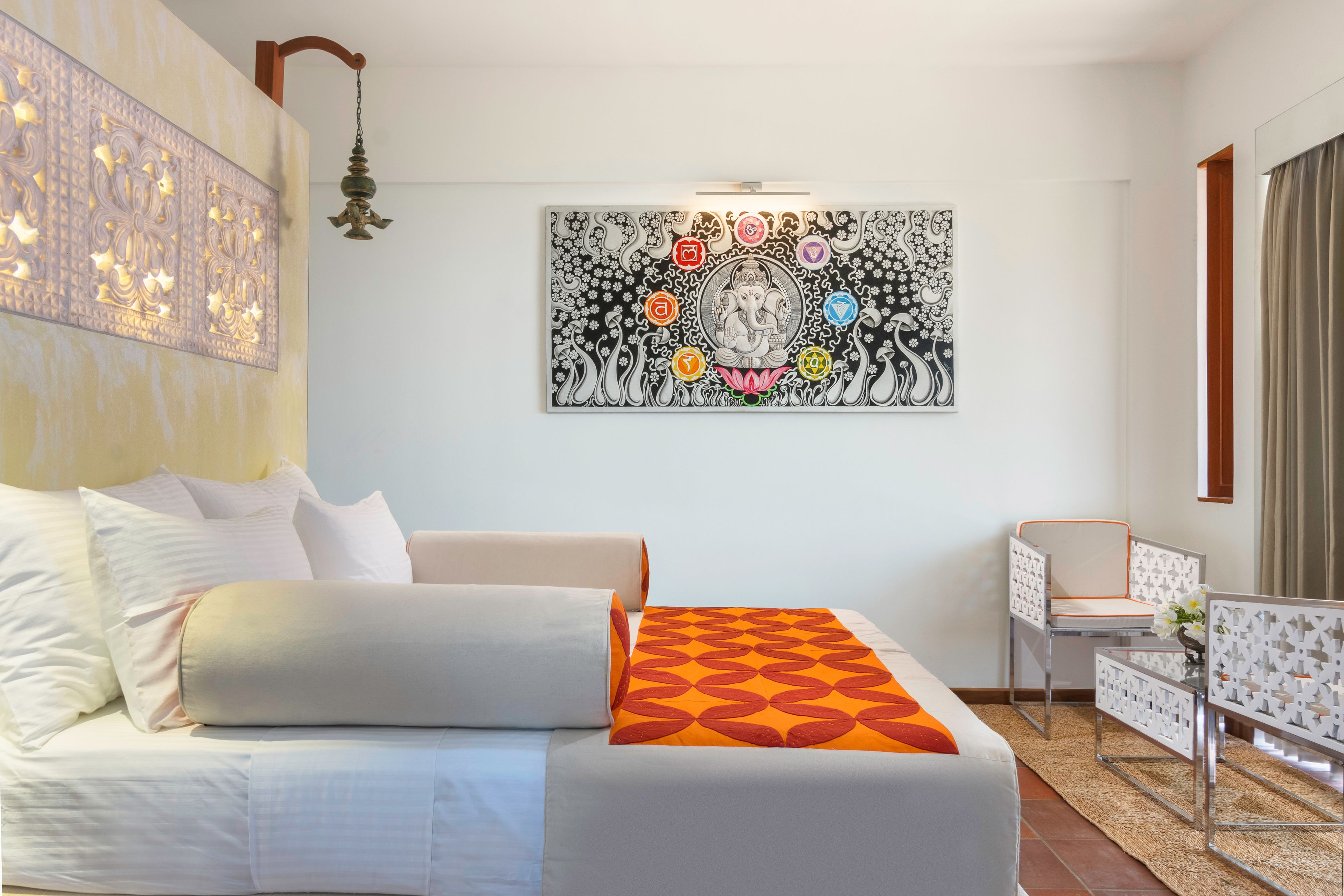 A hotel room with a bed, a chair, a small table, and a wall-mounted artwork.
