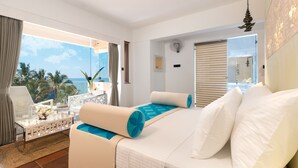 Ein Hotelzimmer mit einem Bett, einer Sitzecke mit Tisch und Stühlen, einem Balkon mit Meerblick und einem großen Fenster.