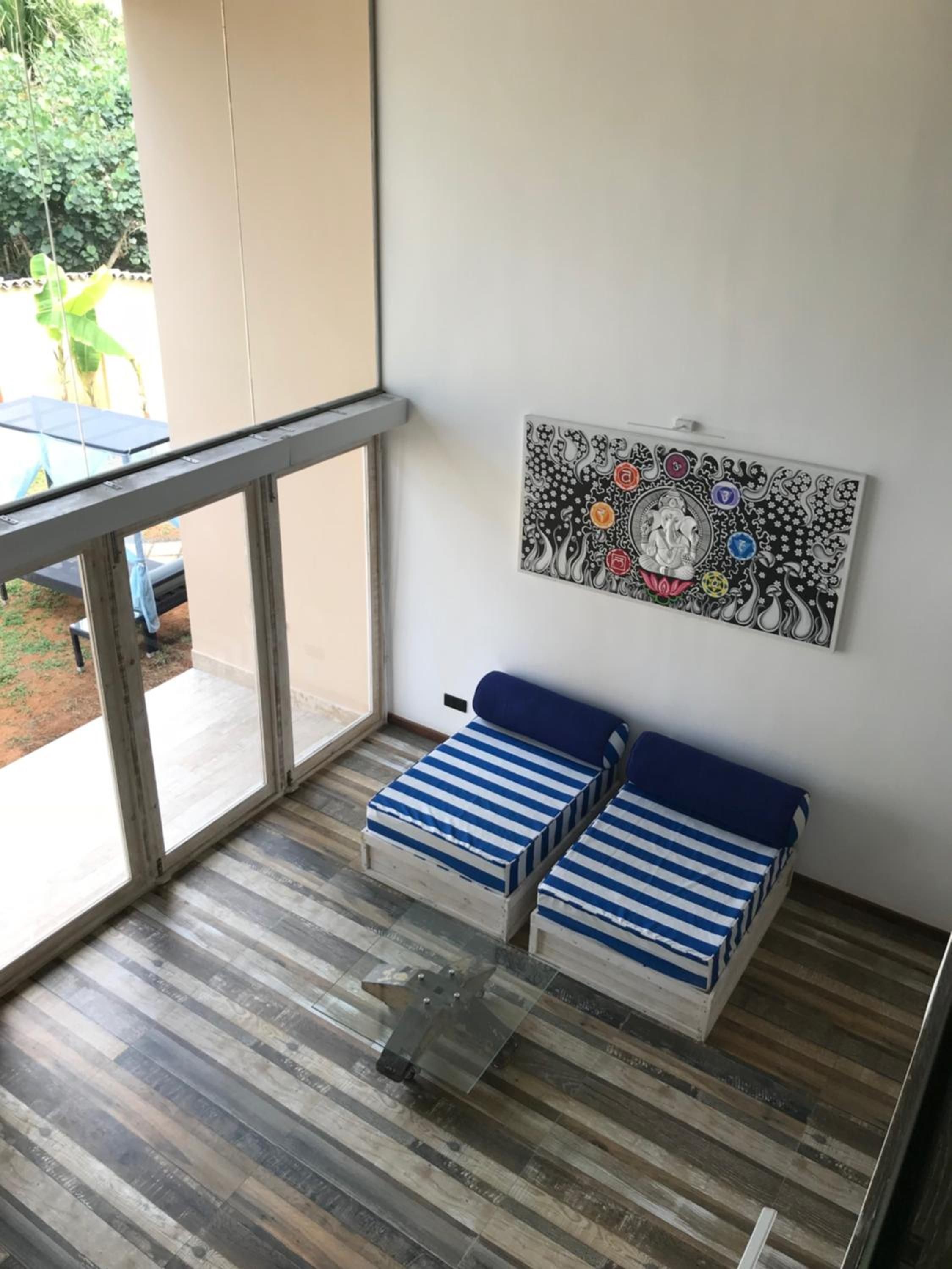 Una habitación con balcón, una cama con ropa de cama a rayas y una obra de arte colgada en la pared.