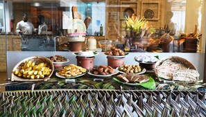 A buffet with various food items and a woven basket of bananas.