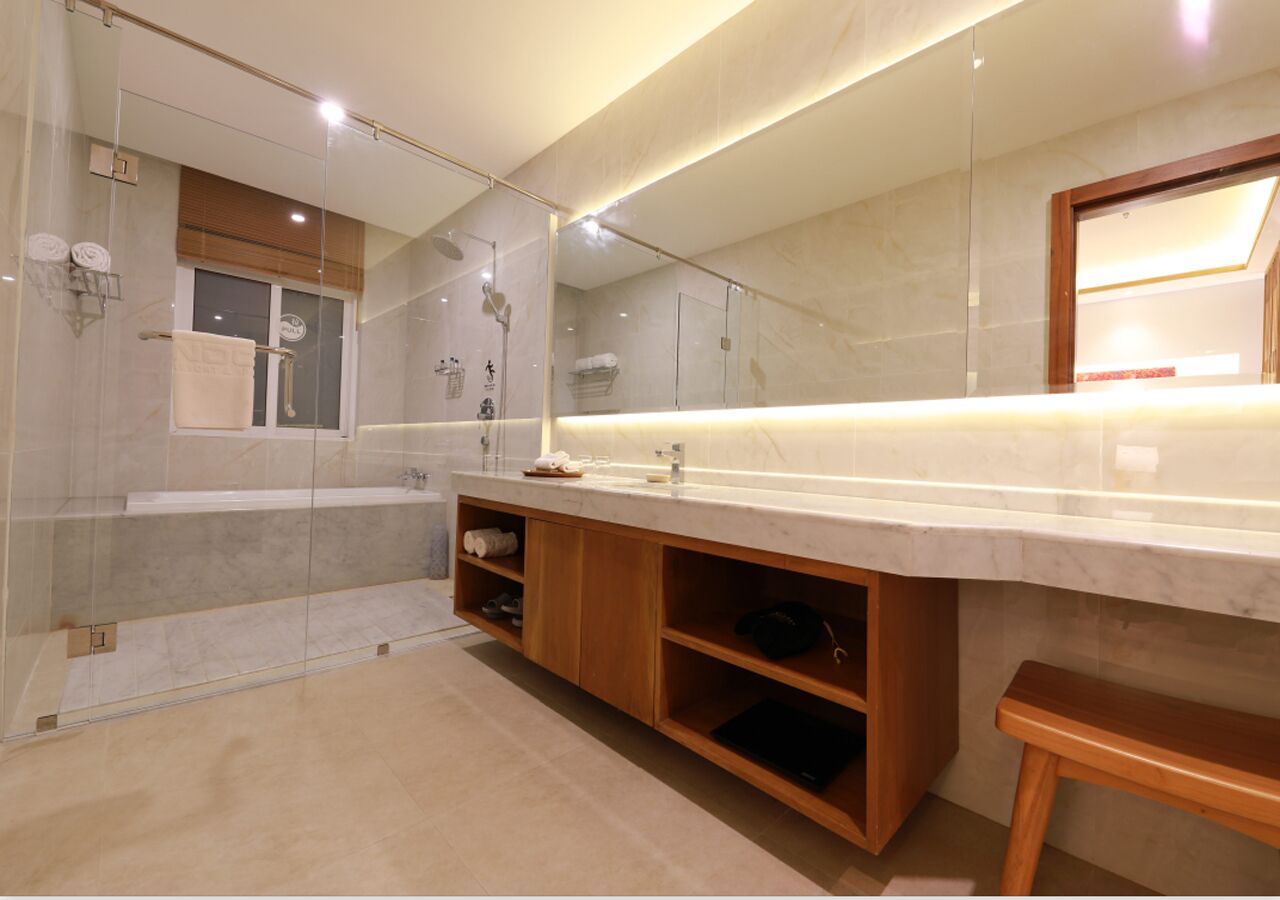 A modern bathroom with a large mirror, a bathtub, and a shower area.