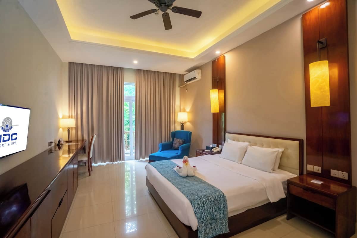 A hotel room with a bed, a desk, a chair, a TV, and a window with curtains.