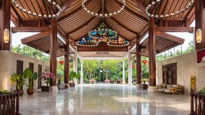 A spacious covered area with a polished floor, wooden beams, and a stained glass window. - NDC Resort (Manado)