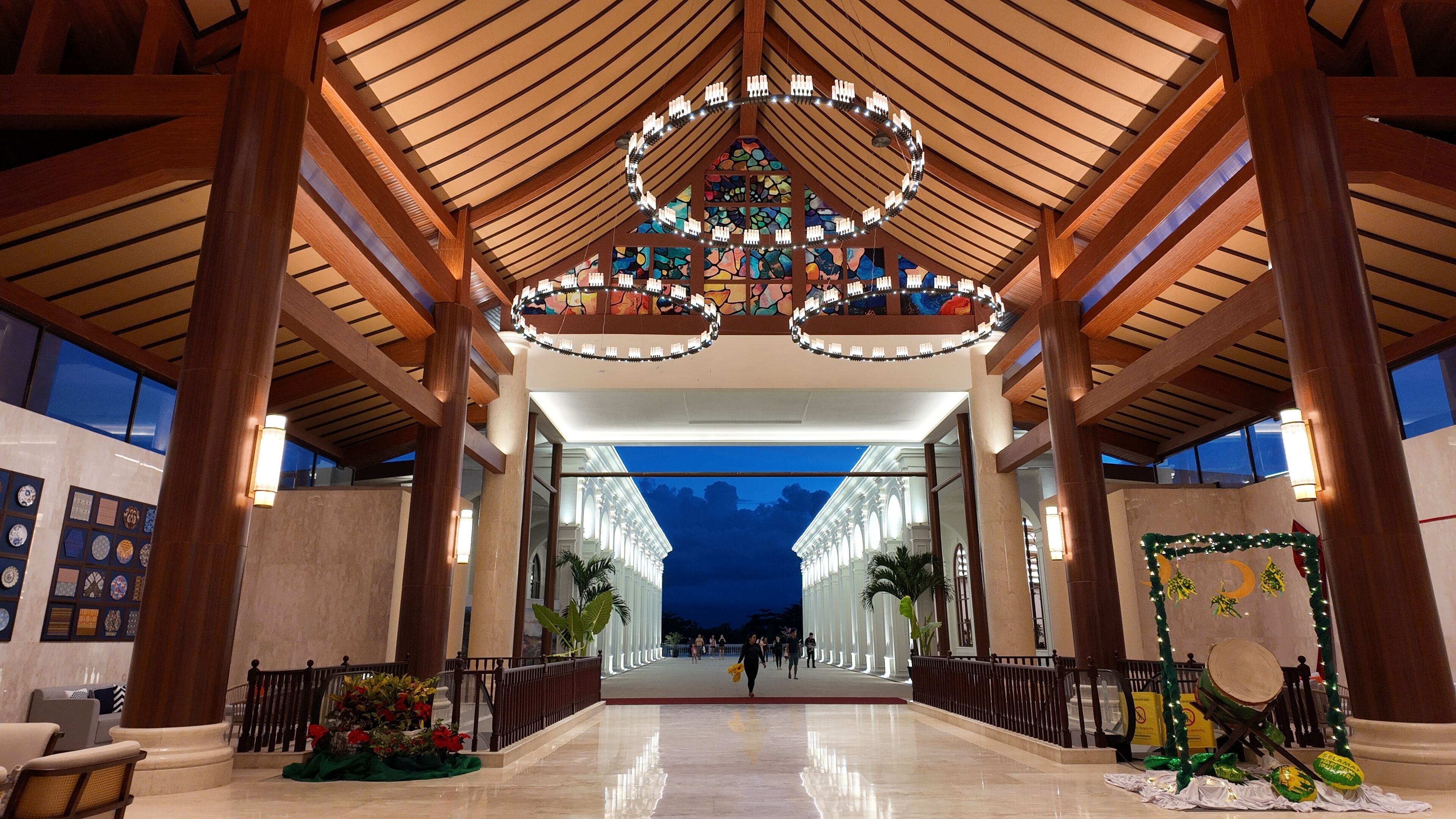 A spacious lobby with a high ceiling, large windows, and a central chandelier.