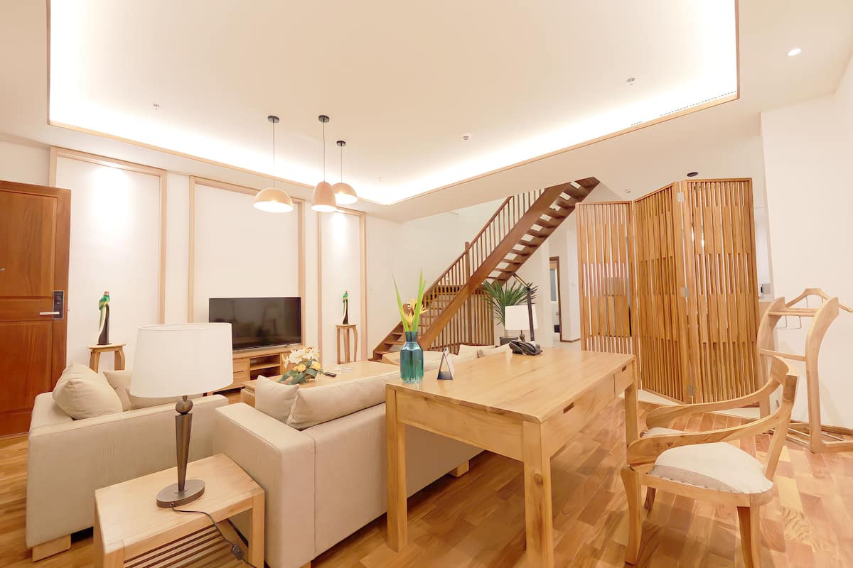 A modern living room with a wooden dining table, sofa, and a TV.
